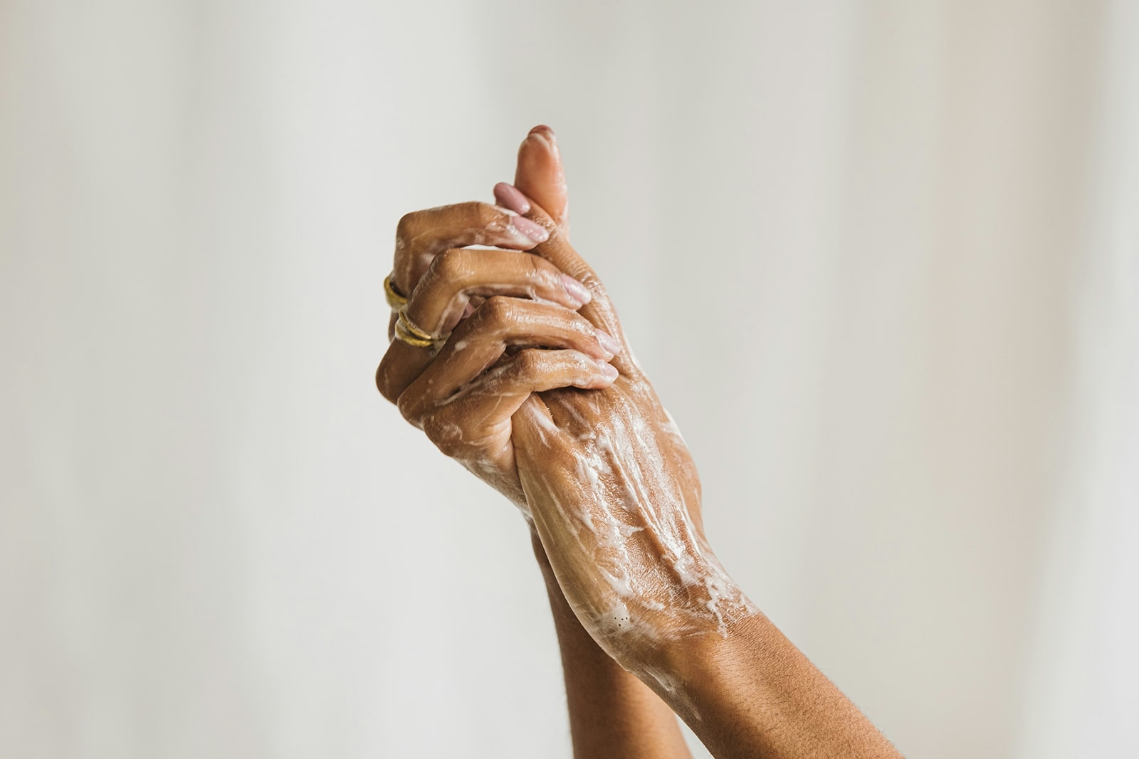 Hands with soap lather against a plain background